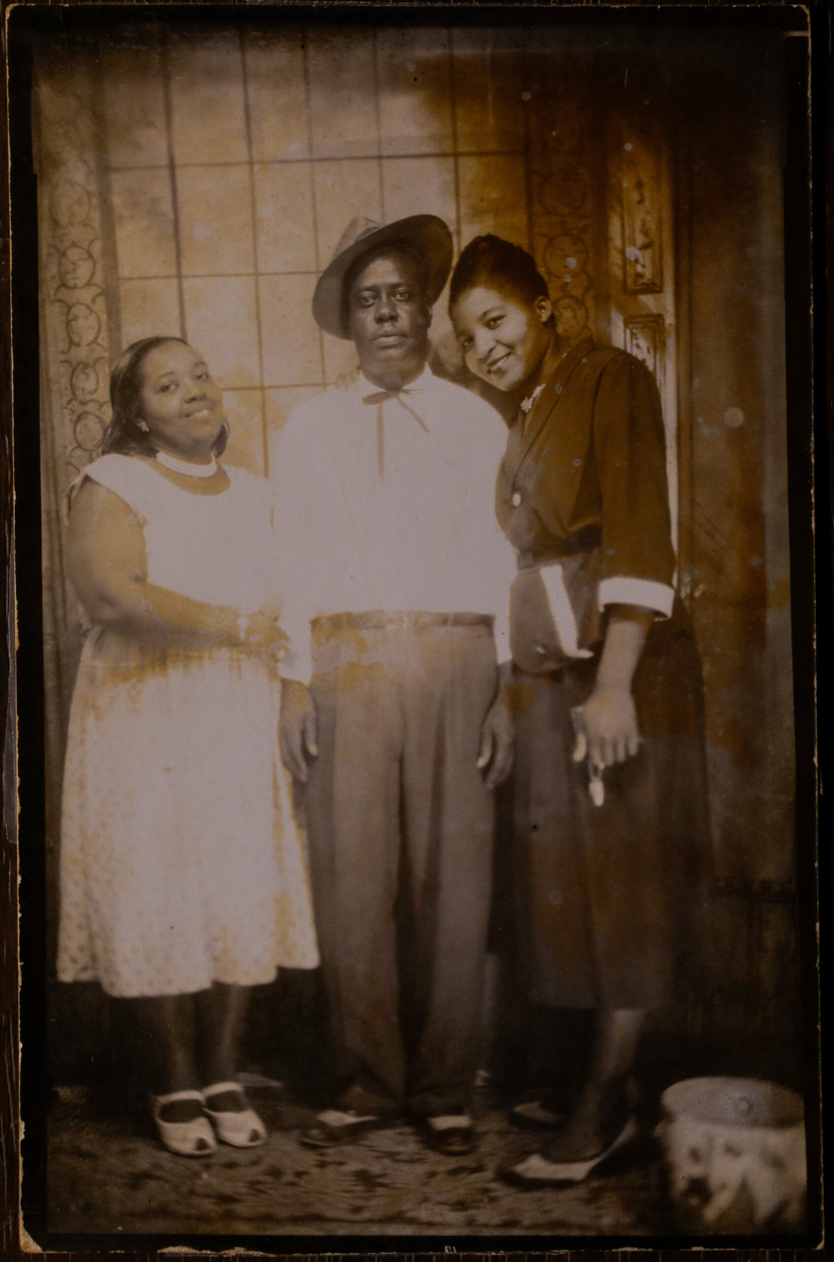 A sepia-toned vertical photo of Jasper Staples, Lucille Fleming, and Rosie Staples dressed in fancy attire.
