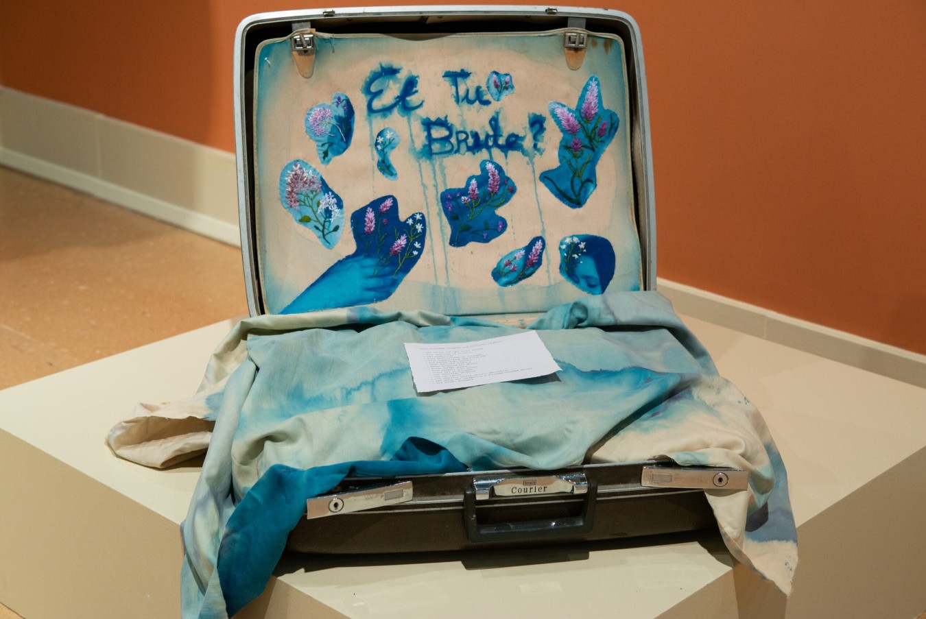 Emma Lorenz (born 2001), Et Tu Brute? (The Fool), 2025; Installation view; Vintage suitcase, acrylic inks, cyanotype printed on fabric lining, embroidery harvested from remains of The Lavender Menace, printed log of suitcase contents