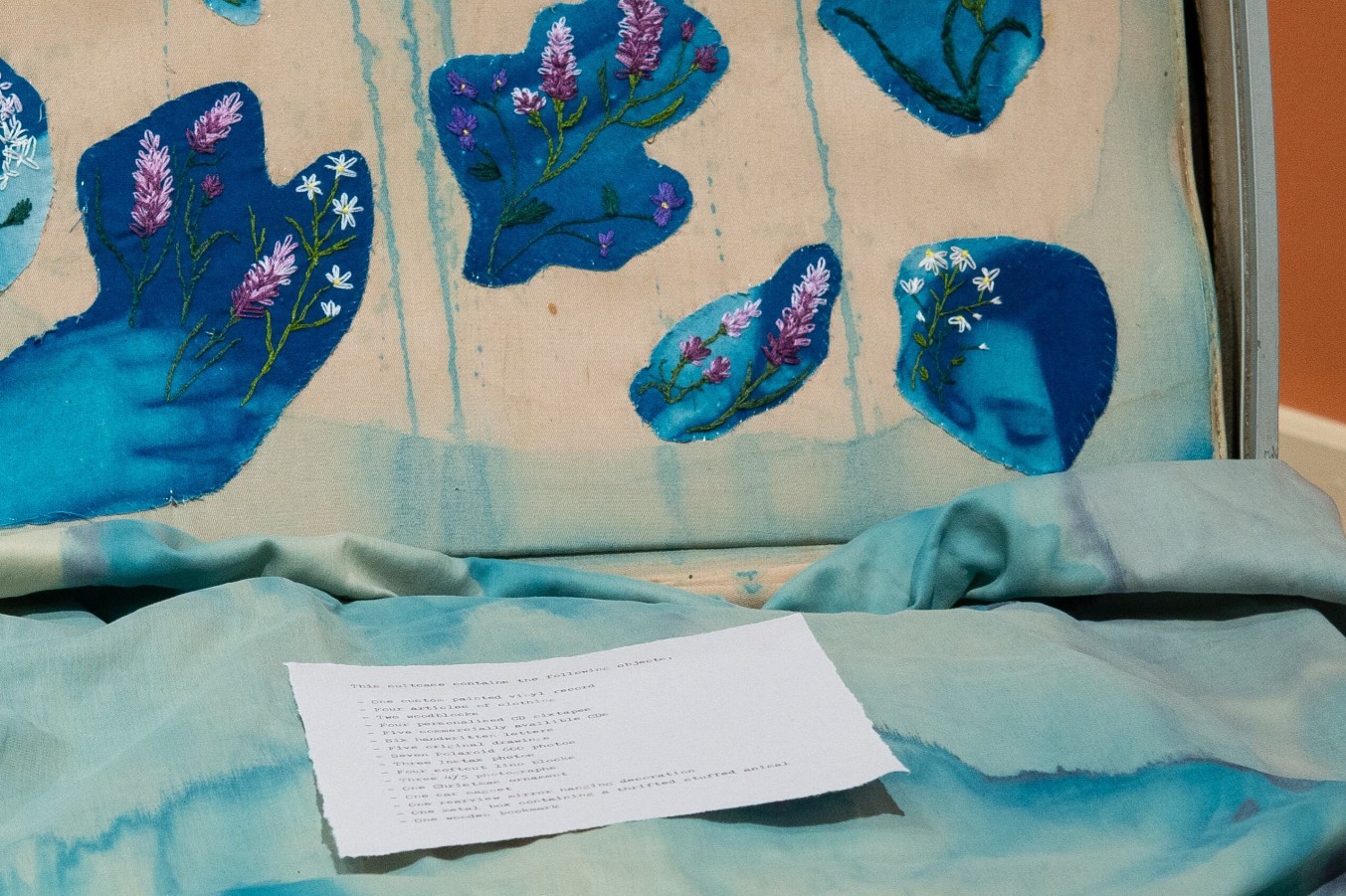 Emma Lorenz (born 2001), Et Tu Brute? (The Fool) (detail), 2025; Installation view; Vintage suitcase, acrylic inks, cyanotype printed on fabric lining, embroidery harvested from remains of The Lavender Menace, printed log of suitcase contents